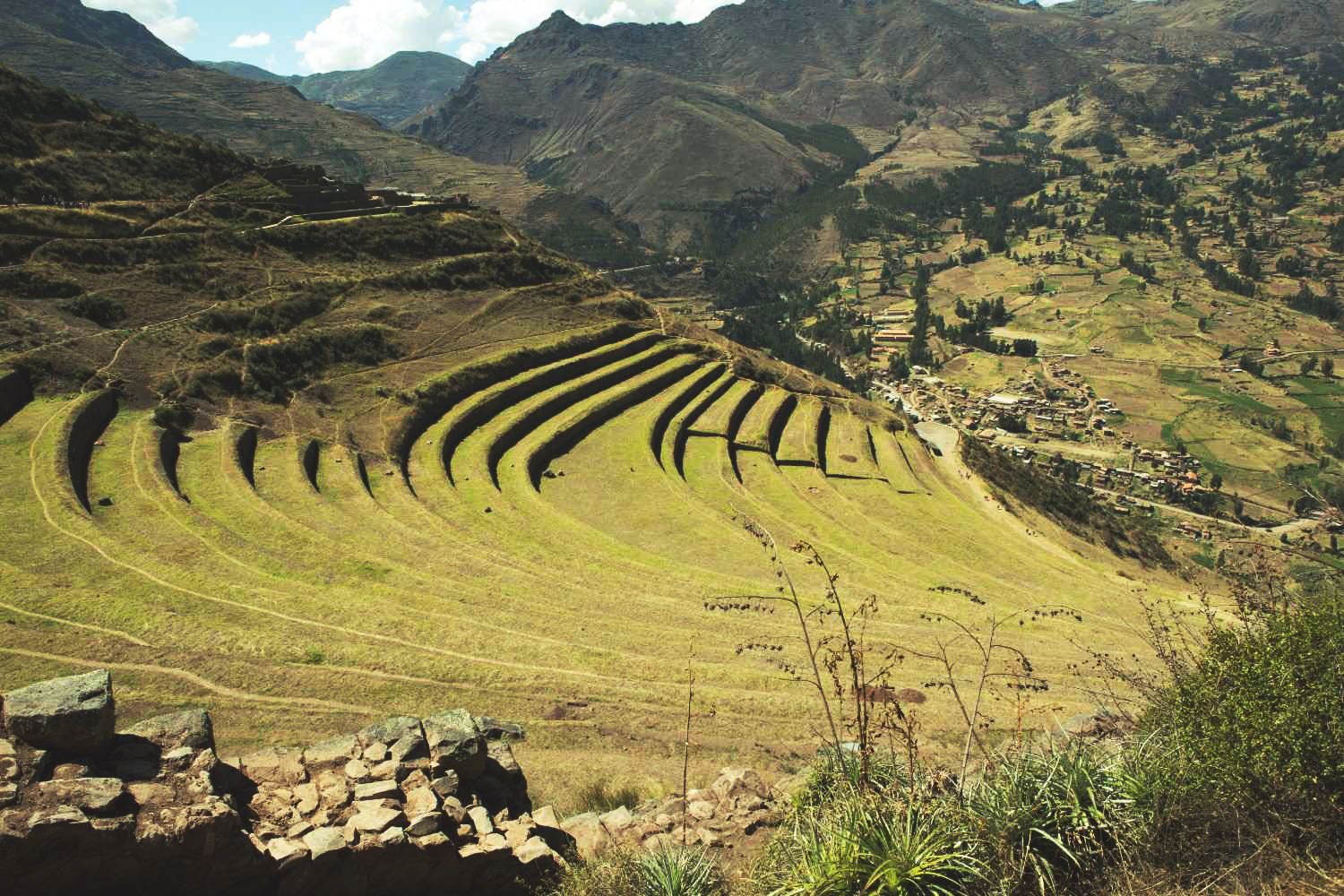 Aerial view of Inca agricultural terraces at the Pisac Archaeological Park, with the village and Andean mountains in the background – cultural tourism and trekking in the Sacred Valley of the Incas.