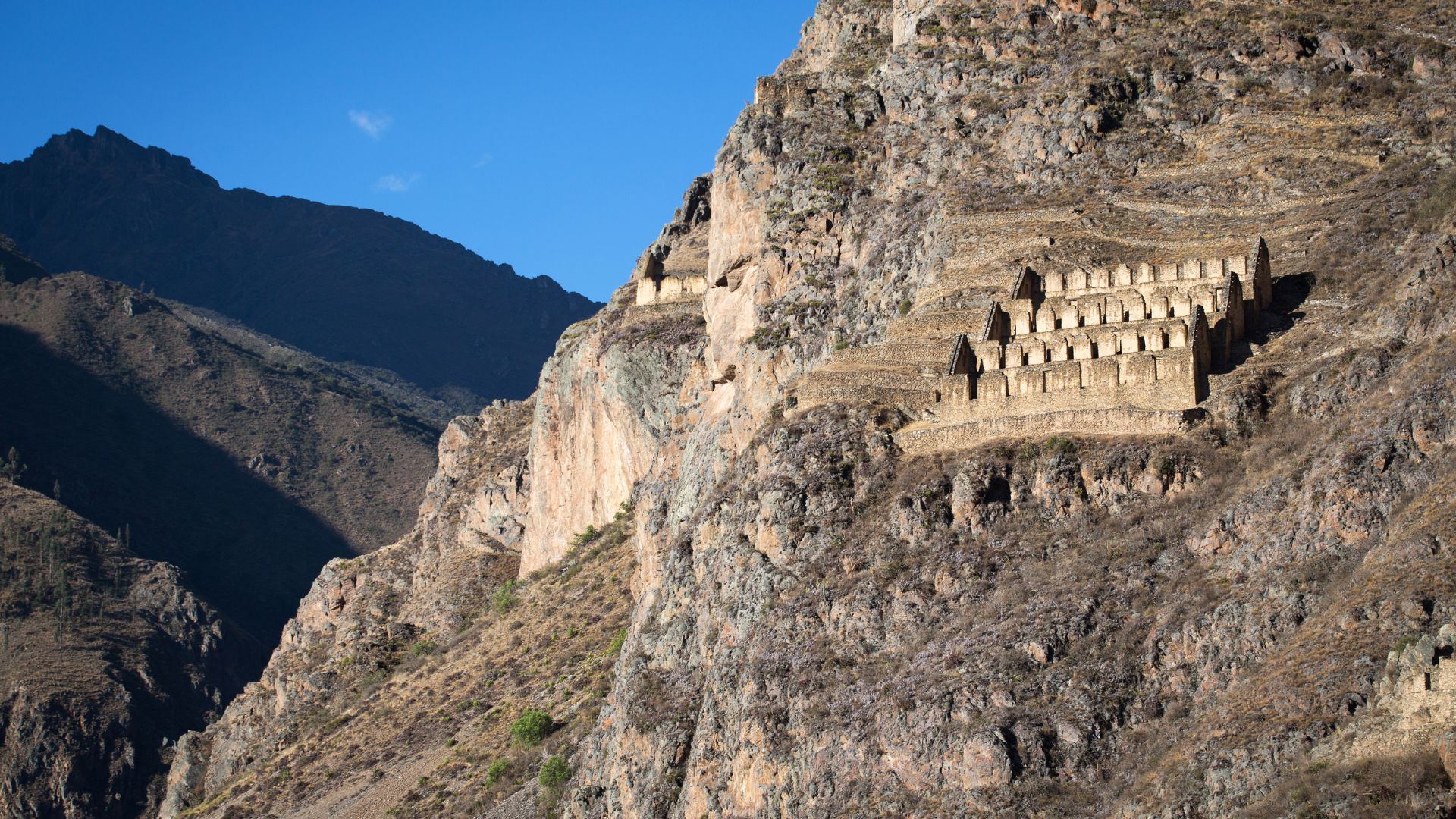 Inca storehouses of Pinkuylluna on the mountainside in Ollantaytambo, Sacred Valley, Peru – ancient stone structures overlooking the valley.