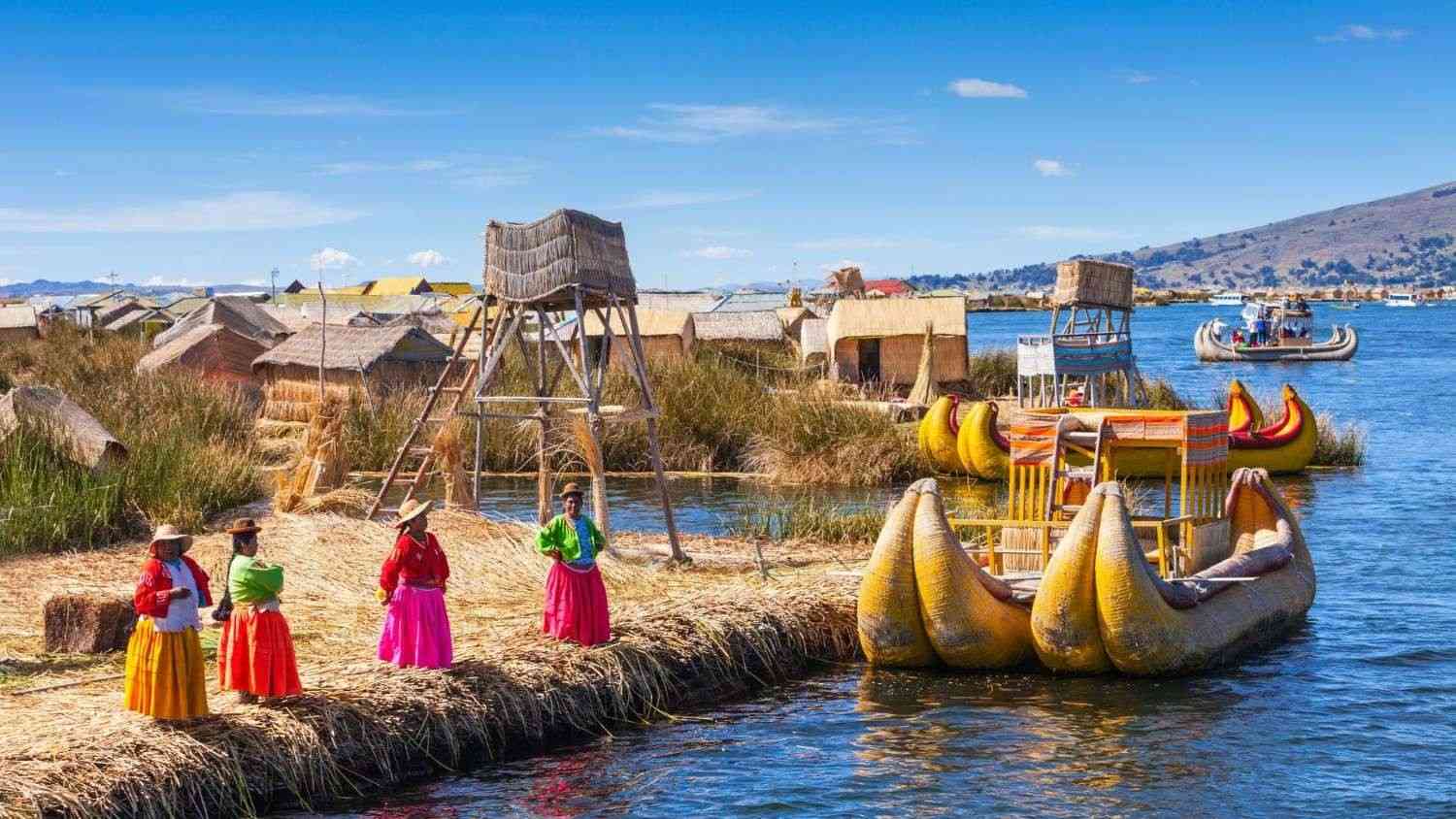 Women of the Uros community on a floating totora reed island in Lake Titicaca altitude, beside traditional boats – cultural and experiential tourism in the Peruvian highlands.