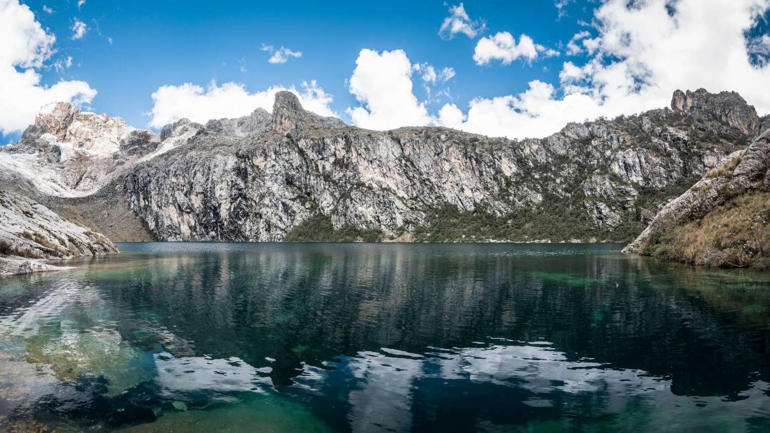 Aguas cristalinas de la Laguna Churup reflejando picos rocosos en la Cordillera Blanca, Perú.