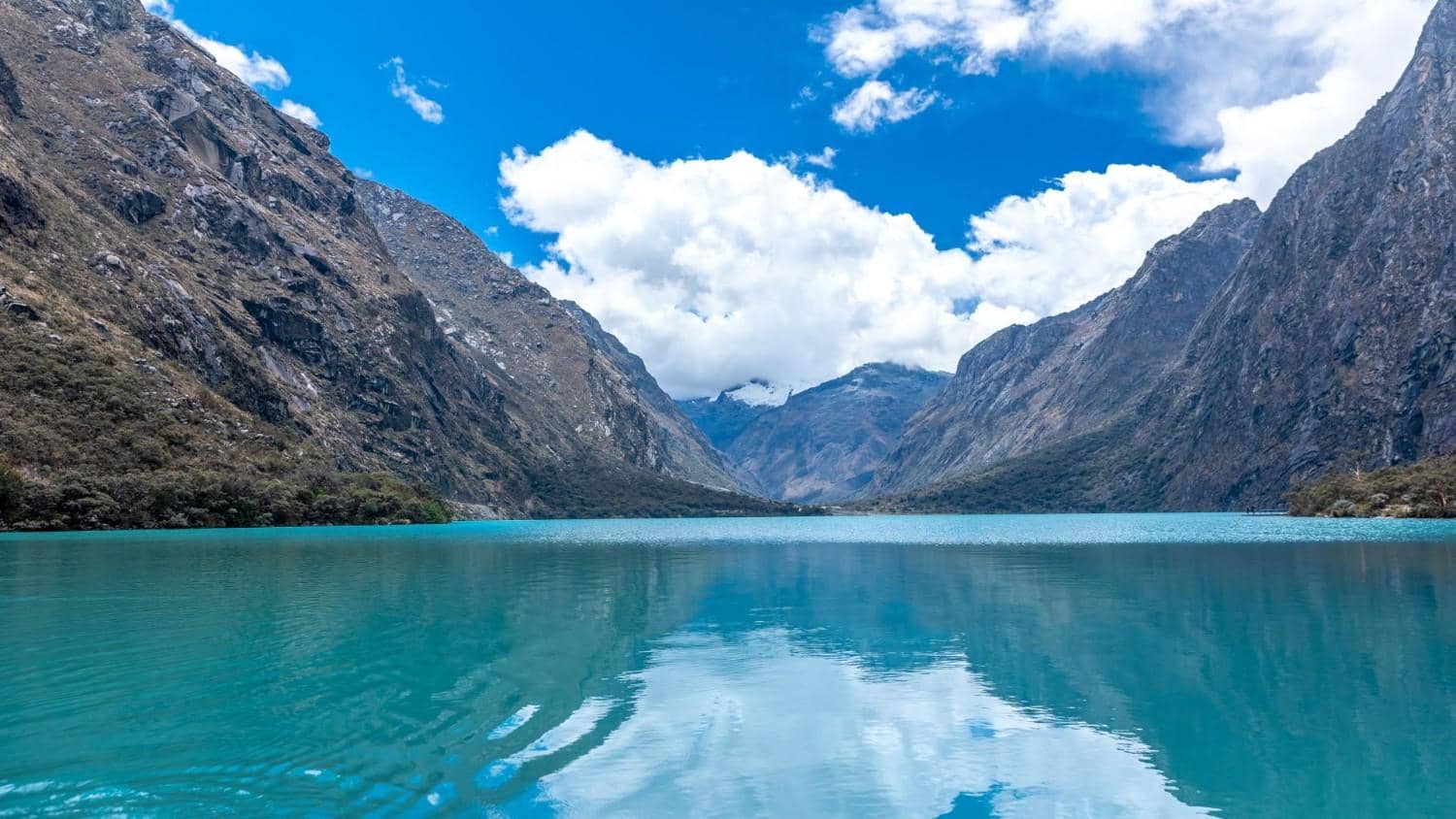 Laguna glaciar de aguas turquesa rodeada de empinados picos andinos en el Parque Nacional Huascarán, Perú.